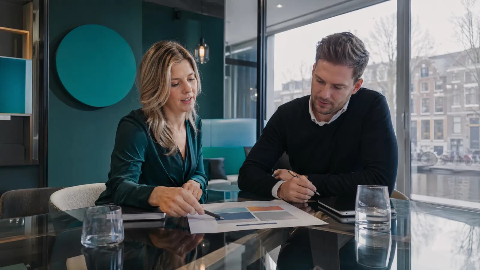 Twee marketeers bespreken een SWOT-analyse voor Google Ads-campagnes in glazen vergaderruimte.